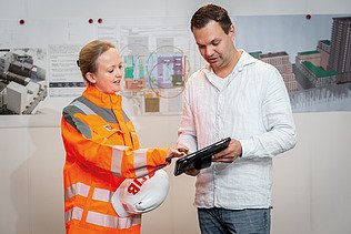 Ein Polier erklärt seinem Team etwas auf einem Tablet