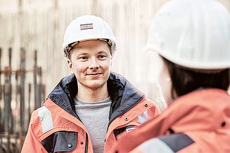 Foto werknemer met bouwhelm kijkt naar werknemer met bouwhelm